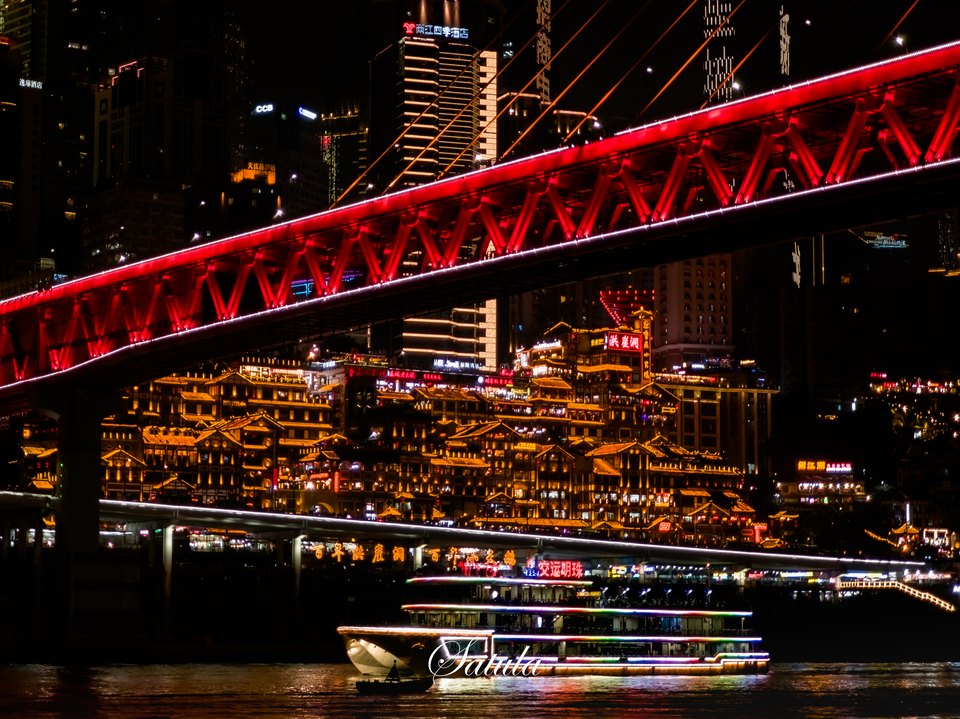 夜色中的红色桥梁与江面游船